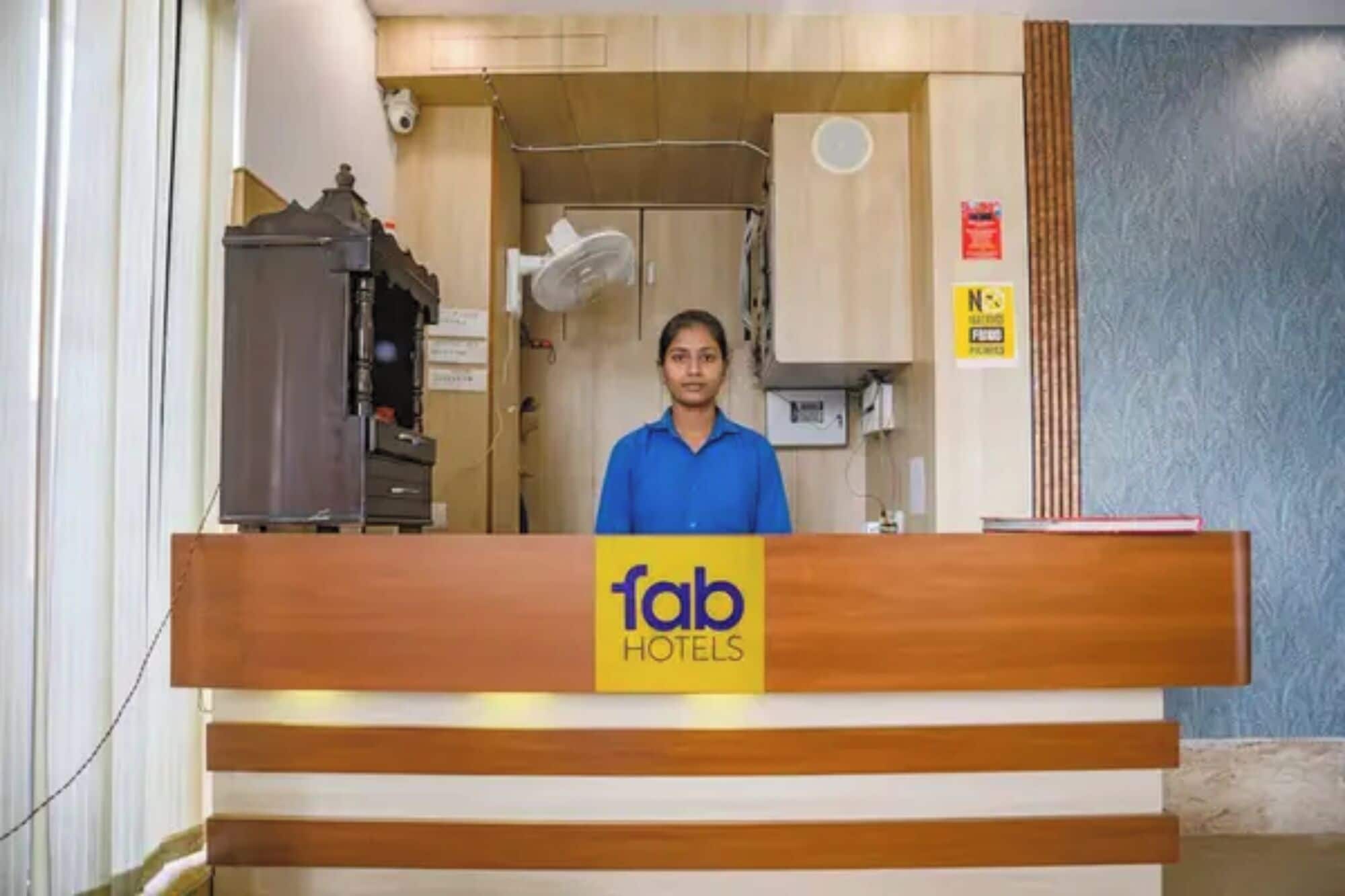 A reception desk with a sign for 'fab hotels' and a person standing behind it.