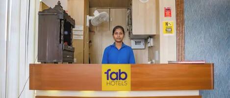 A reception desk with a sign for 'fab hotels' and a person standing behind it.