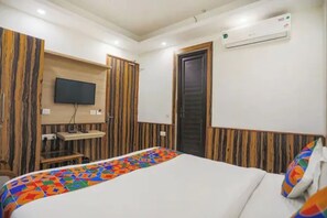 Quarto de hotel com uma cama, televisão fixada na parede e ar condicionado.