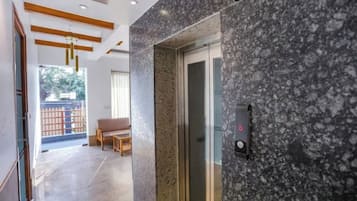 Een hotel lobby met een marmeren receptiebalie, een glazen lift en een zithoek met uitzicht op het omliggende landschap.