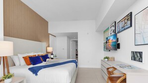Ein modernes Hotelzimmer mit Bett, Nachttisch, Lampe und Schreibtisch mit Stuhl.