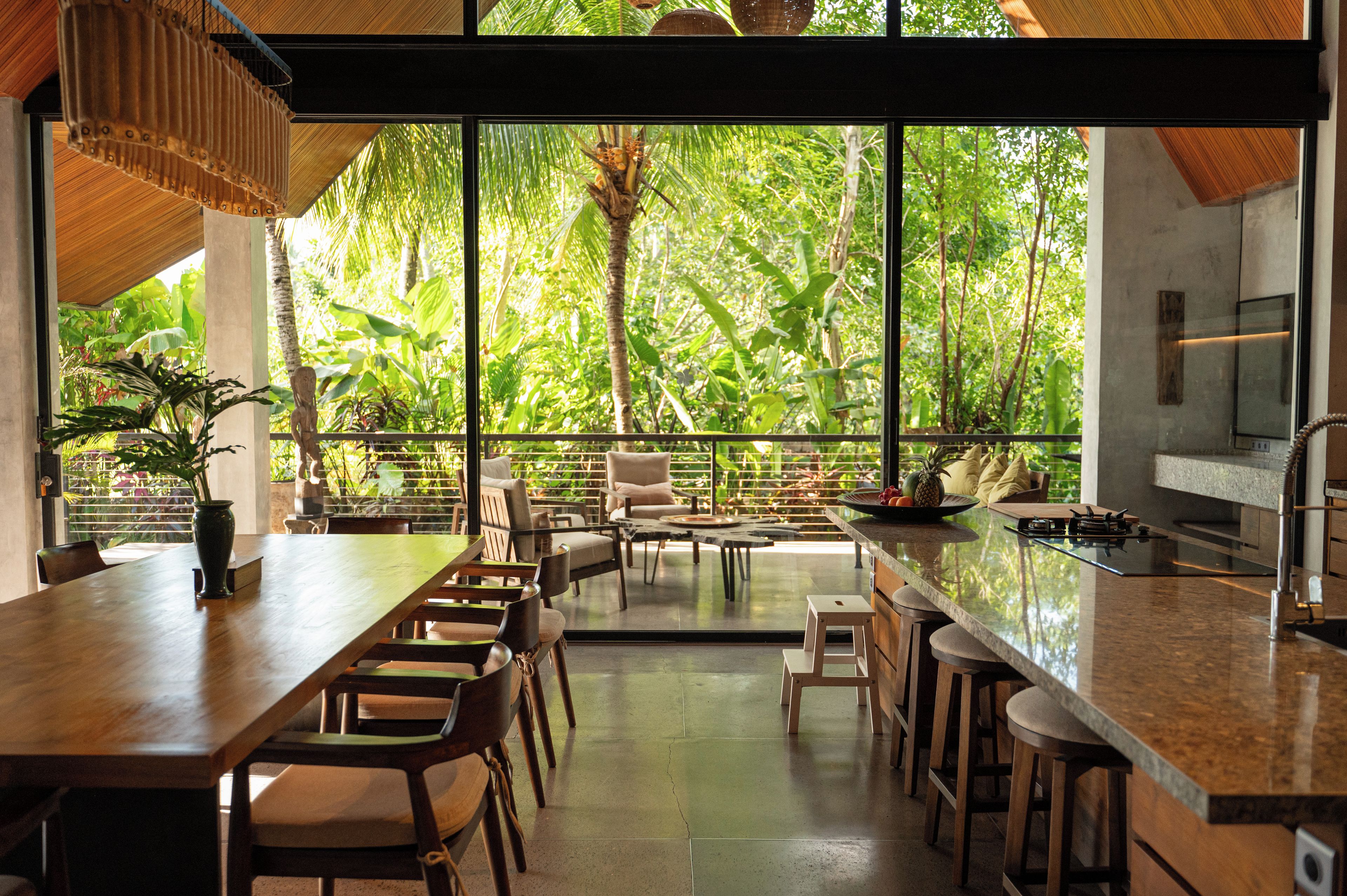 A modern kitchen with a large island, bar stools, and a dining area with chairs and tables.