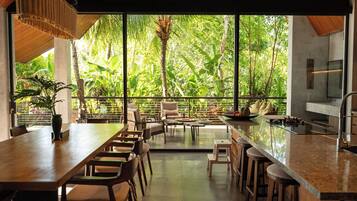 A modern kitchen with a large island, bar stools, and a dining area with chairs and tables.