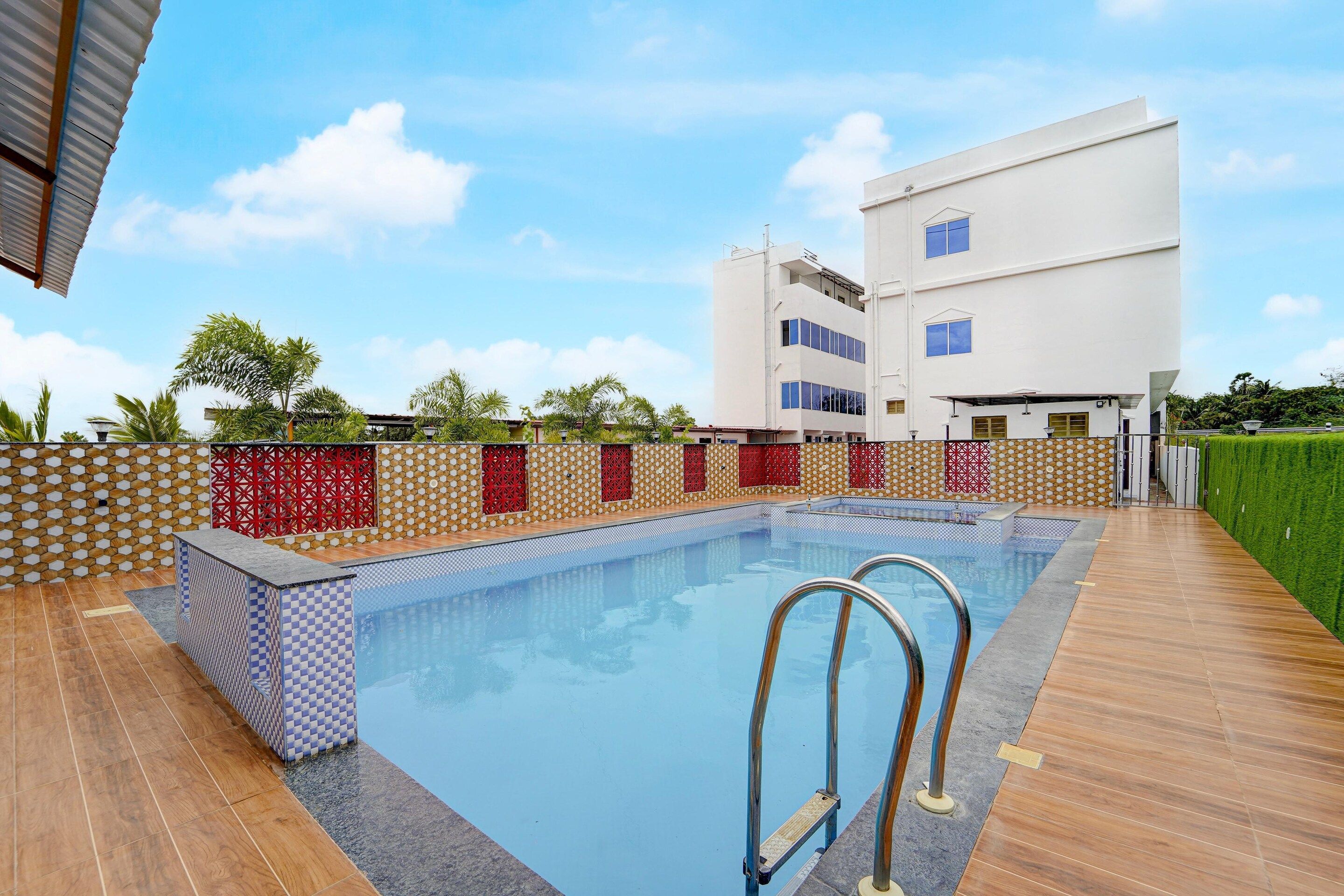 A swimming pool with a wooden deck, surrounded by a low wall with patterned tiles and red decorative panels.