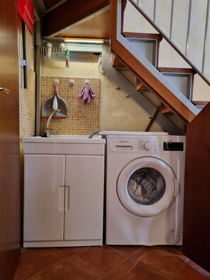 A compact laundry area with a washing machine and a cabinet. - Historic Loft, just a short walk from the train station and the historic district (Catania)