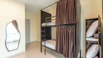 Habitación con literas, cortina, espejo y unidad de almacenamiento con almohadas.