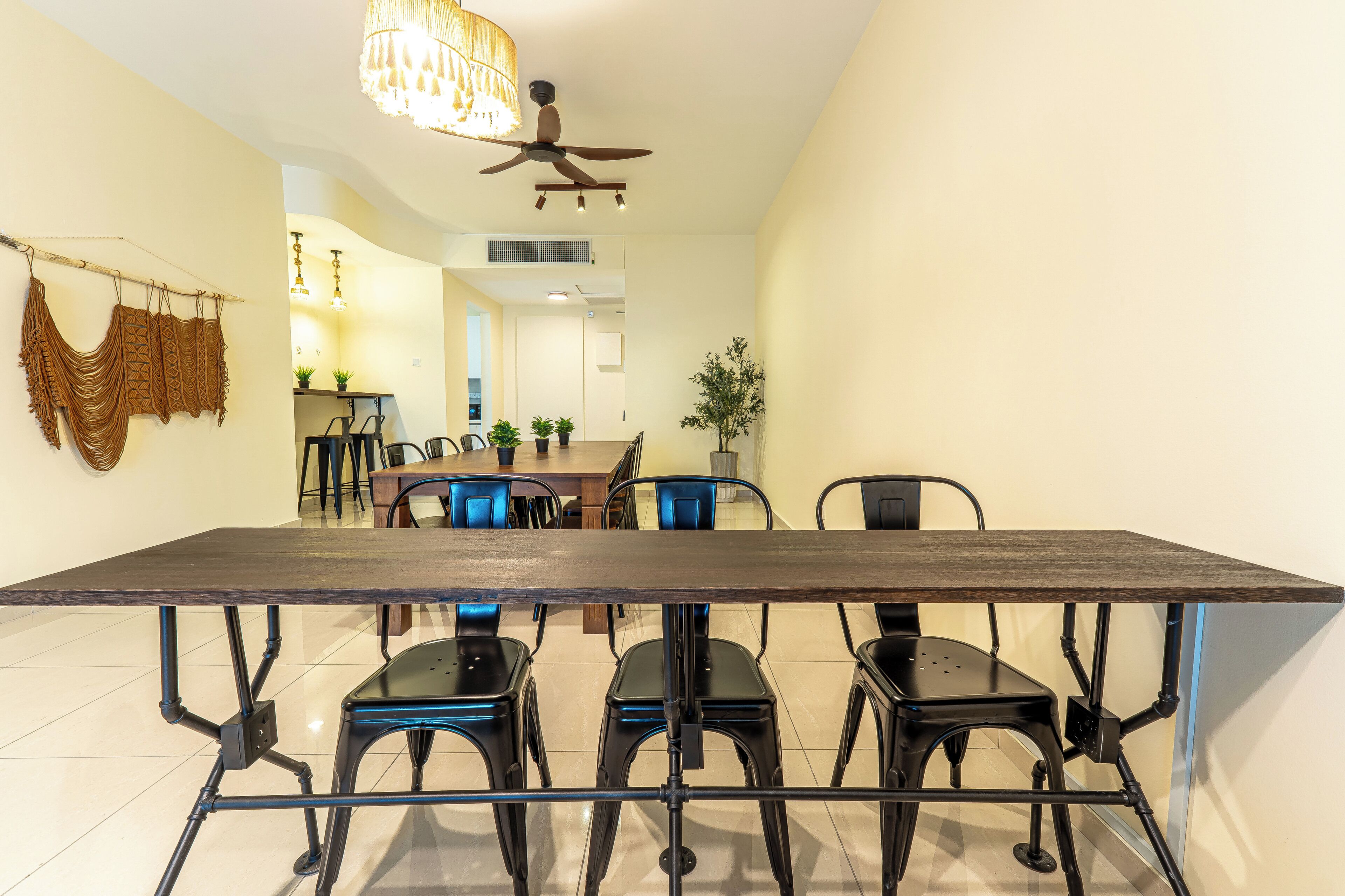 A dining area with a long table, chairs, and a ceiling fan.
