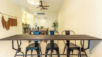 A dining area with a long table, chairs, and a ceiling fan.