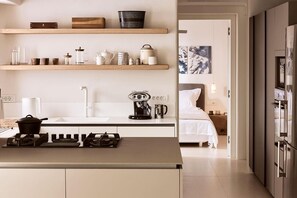 Eine moderne Küche mit Gaskochfeld, Kaffeemaschine und einem Essbereich mit weißem Tisch und Stühlen.