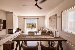 A modern interior with a dining area, sofa, and a view of the outdoors. - East Coast Villa – Dream Living (Rafina)