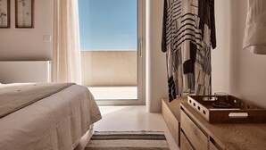 Ein Schlafzimmer mit einem Bett, einer Holzkommode, einem Spiegel und Blick zum Himmel.