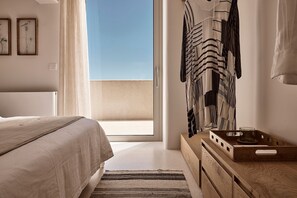 Ein Schlafzimmer mit einem Bett, einer Holzkommode, einem Spiegel und Blick zum Himmel.