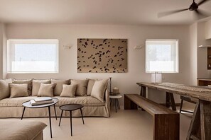 Ein Wohnzimmer mit einer Couch, zwei Beistelltischen, einer Holzbank und einem Deckenventilator.
