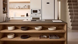 Eine moderne Küche mit eingebauter Mikrowelle, einer Kaffeemaschine und einem weißen Kühlschrank.