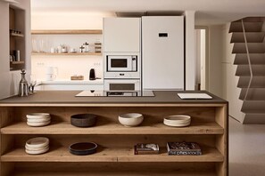 Eine moderne Küche mit eingebauter Mikrowelle, einer Kaffeemaschine und einem weißen Kühlschrank.