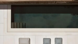 Ein moderner Außenbereich mit Pool, zwei Liegestühlen und einem kleinen Tisch.