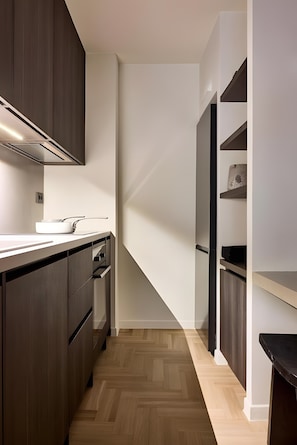 Een moderne keuken met donkere kastjes, een wit aanrechtblad en een ingebouwde oven.