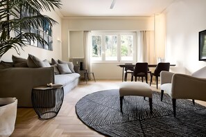 A modern living room with a sofa, chairs, a coffee table, and a large window with curtains. - Estia Athens – Your Luxurious Urban Retreat (Athens)