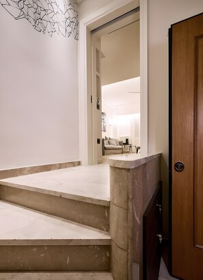 A staircase leading to a room with a bed, a nightstand, and a lamp. - Estia Athens – Your Luxurious Urban Retreat (Athens)