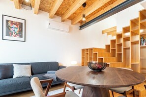 Ein modernes Wohnzimmer mit einem runden Holztisch, einem grauen Sofa und einer Holzbibliothek.