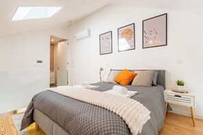 A modern bedroom with a large bed, a bedside table with a plant, and artwork on the wall. - Modern Apt in Historic Porto's Largo da Lapa (Porto)