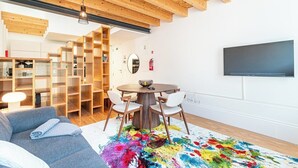 Uma sala de estar moderna com teto de madeira, uma mesa de jantar redonda e um tapete colorido.