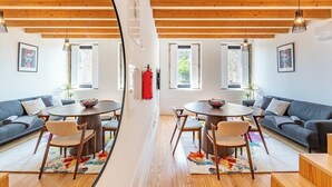 Um quarto com uma mesa de jantar e cadeiras, um sofá e um extintor de incêndio na parede.