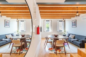 Ein Zimmer mit Esstisch und Stühlen, einer Couch und einem an der Wand befestigten Feuerlöscher.