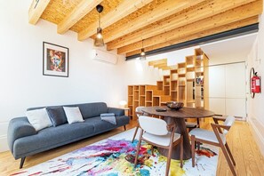Un saló modern amb un sofà, una taula rodona i una alfàbbra abstracta i colorida.