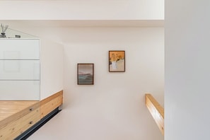 A hallway with a wooden bench, a white cabinet, and two framed pictures on the wall. - Modern Apt in Historic Porto's Largo da Lapa (Porto)