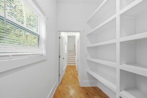 A narrow hallway with white walls, a wooden floor, and a staircase leading to another room. - New Luxury Family-Friendly Getaway 4BR Home Near Atlanta/Sleeps 14+ (Lawrenceville)