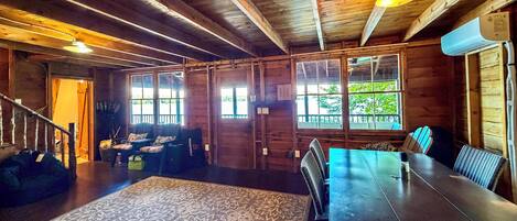 A wooden interior with a dining table, chairs, and a patterned rug.