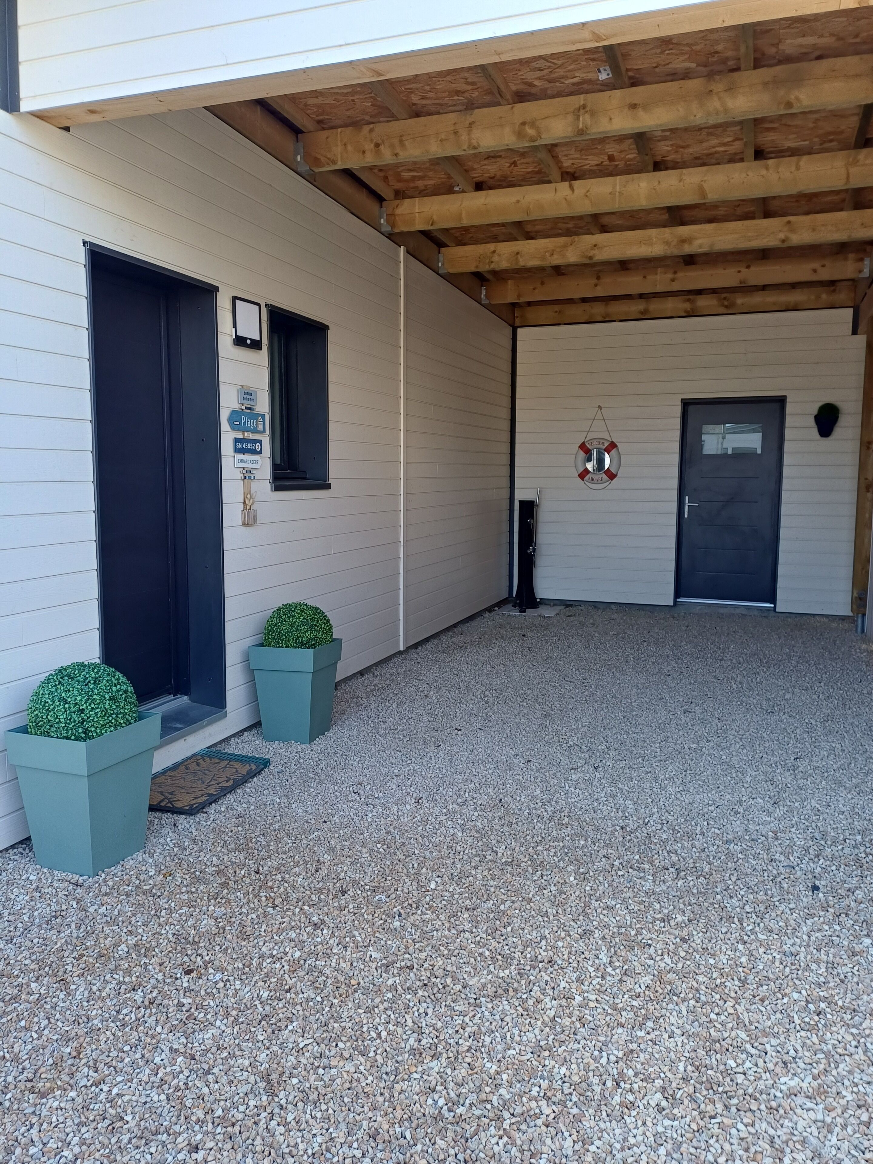 A covered outdoor area with a gravel floor, a wooden ceiling, and a door with a sign.