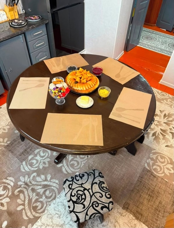 A round dining table with a central pie, surrounded by various dishes and napkins.