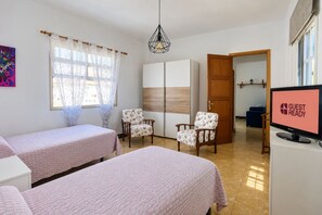 A hotel room with two beds, a TV, a wardrobe, and a door leading to another room. - GuestReady - Villa Mountain Sea Views (Hermigua)