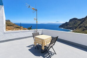 A balcony with a table and chairs, overlooking a coastal landscape with a clear sky. - GuestReady - Villa Mountain Sea Views (Hermigua)