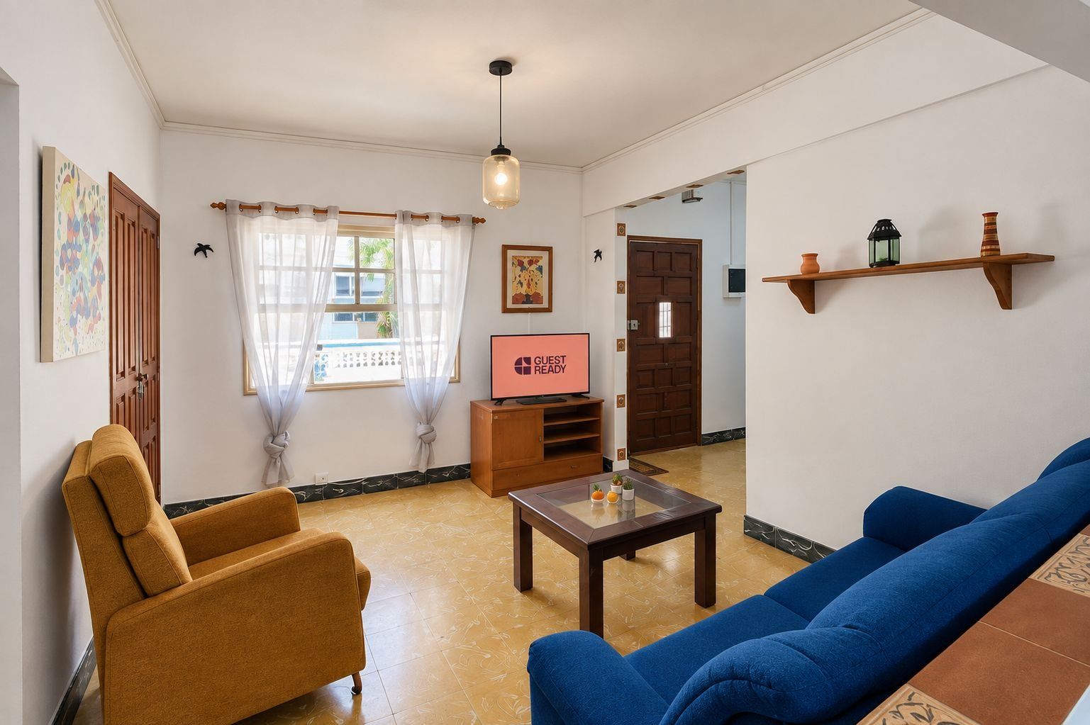 Ein Wohnzimmer mit Sofa, Sessel, Fernseher und Couchtisch.