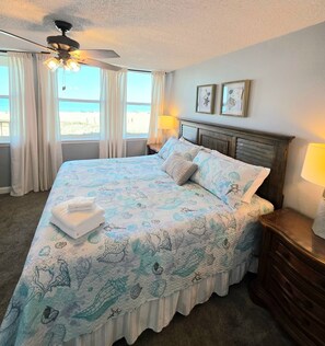 A bedroom with a bed, curtains, a ceiling fan, and a view of the beach. - Wonderful 3-bedroom condo with ocean views in charming Gulf Shores (Gulf Shores)