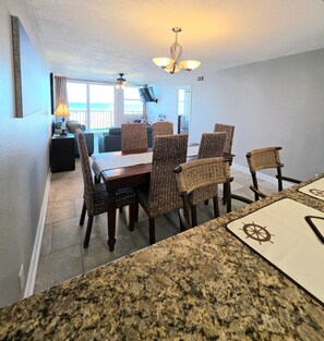 A dining area with a table and chairs, a ceiling fan, and a view to the outside. - Wonderful 3-bedroom condo with ocean views in charming Gulf Shores (Gulf Shores)