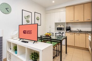 A modern kitchen with white cabinets, a microwave, a coffee maker, and a dining area with a glass table and chairs. - GuestReady - Town Centre Apartment (Tazacorte)