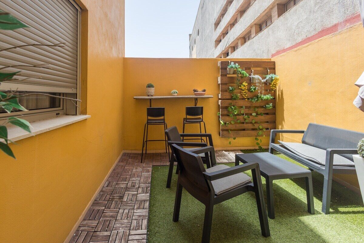 A small outdoor seating area with a table and chairs, a bench, and a vertical garden.