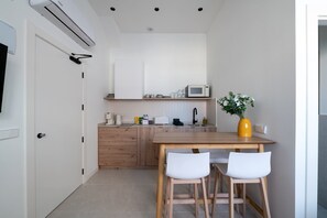 A compact kitchen with a wooden table, two white chairs, a microwave, and a yellow vase with flowers. - GuestReady - Estudio super acogedor en Madrid (Madrid)