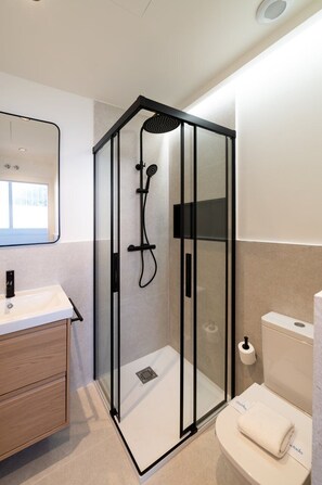 A modern bathroom with a glass-enclosed shower, a sink, and a toilet. - GuestReady - Estudio super acogedor en Madrid (Madrid)