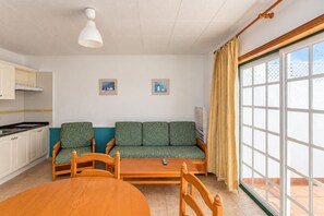 A compact living space with a kitchenette, a sofa set, a dining table, and a large window. - GuestReady - Colon I 10 2 pax (Los Quemados)