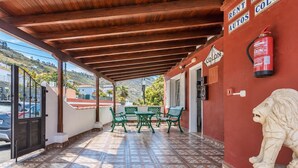 Zona exterior coberta amb taula, cadires, extintor i estàtua de lleó.