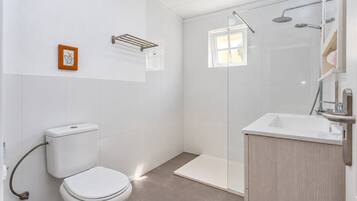 Un baño moderno con inodoro, ducha y lavamanos.