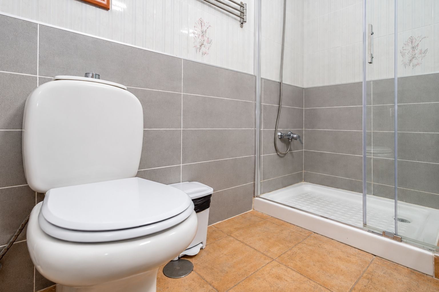 Un baño con inodoro, un cubo de basura y zona de ducha.