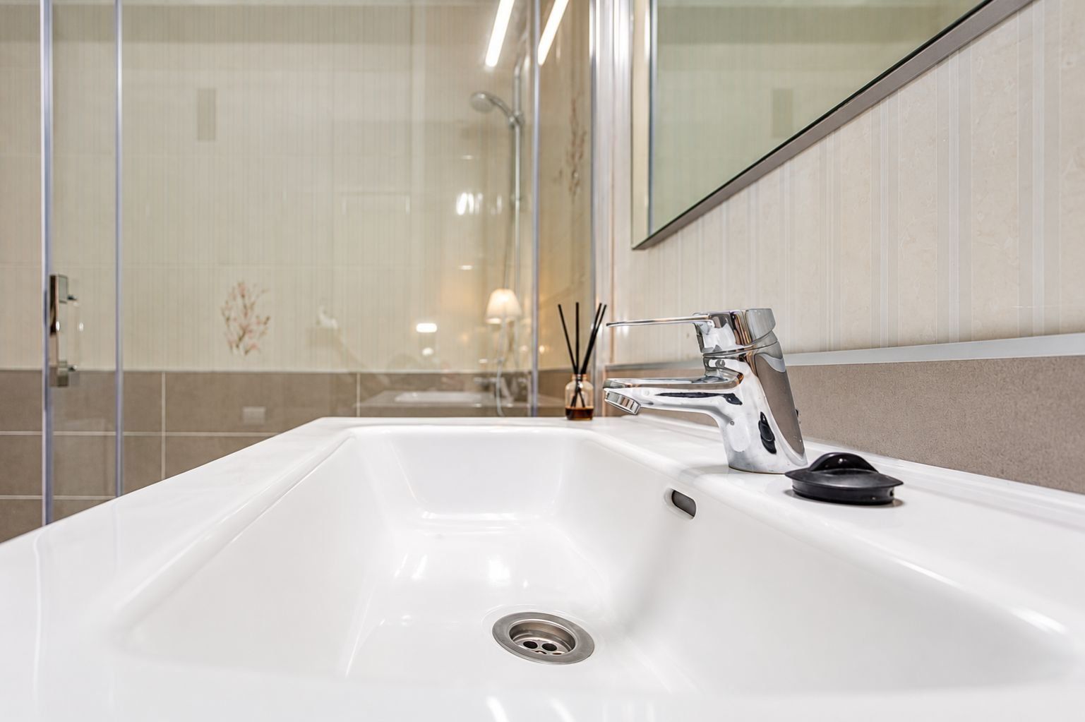 Un baño moderno con un lavamanos blanco, grifo cromado y un espejo encima.