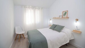 Una camera da letto con un letto, una sedia, un comodino e una mensola a parete.