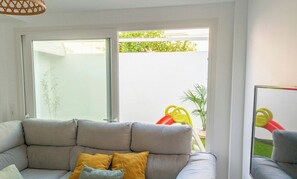 Ein modernes Wohnzimmer mit einem grauen Sofa, einem gelben Kissen und einem großen Fenster.
